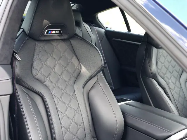 Interieur van een BMW M8 Gran Coupé Competition met zwart gewatteerde lederen stoelen met het "M8"-logo op de hoofdsteun.