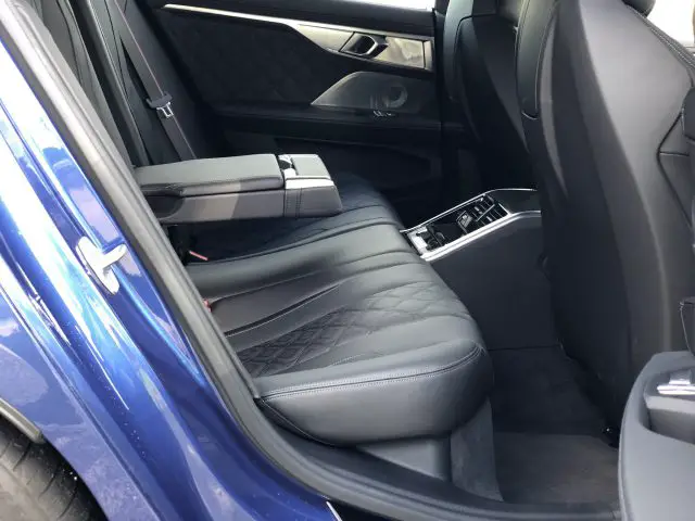 Het interieur van de BMW M8 Gran Coupé Competition is voorzien van zwart lederen stoelen met stiksels in ruitpatroon, een armsteun met bekerhouders en deurpanelen versierd met metallic accenten, die bij elke bocht luxe uitstralen.