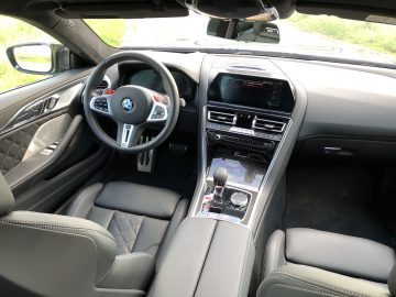 Interieur van de BMW M8 Gran Coupé Competition, met met leer bekleed stuur, digitaal display, versnellingspook en comfortabele lederen stoelen.