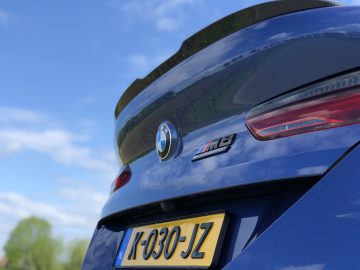 Close-upafbeelding van de achterkant van een blauwe BMW M4 met zichtbaar kenteken "K-030-JZ" en het BMW-embleem, met designelementen die doen denken aan zijn broer, de BMW M8 Gran Coupé Competition.