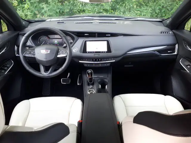 Binnenaanzicht van een moderne Cadillac XT4, met een strak dashboard met aanraakscherm, een multifunctioneel stuur en witleren stoelen.
