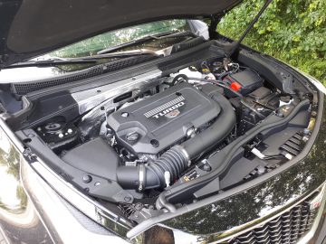 Open motorkap van een Cadillac XT4 met een turbomotor met verschillende componenten en onderdelen zichtbaar.