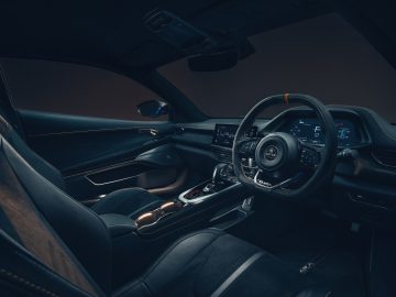 Binnenaanzicht van een moderne auto, gericht op de bestuurderszijde met een strak stuur, een digitaal dashboard en eigentijdse designelementen die doen denken aan de Lotus Emira, alles in een slecht verlichte omgeving.