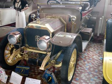 Oldtimer tentoongesteld in het Musée Automobile de Vendée, omgeven door informatieborden en een mannequin gekleed in kledij uit het begin van de 20e eeuw.