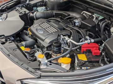 Close-up van een Subaru Outback-motorruimte met verschillende componenten en aansluitingen, met zwarte, rode en gele onderdelen.