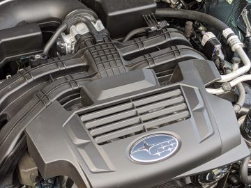 Close-up van een Subaru Outback-motor met de gedetailleerde componenten, inclusief de motorkap met het Subaru-logo prominent weergegeven.