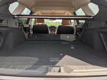 De afbeelding toont het interieur van een Subaru Outback met de achterbank neergeklapt, waardoor een grote, vlakke laadruimte ontstaat. Het zicht is vanaf de open achterklep, kijkend naar de voorstoelen en het dashboard.