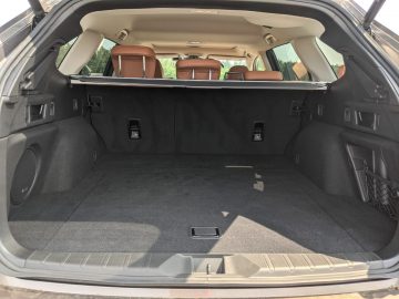 Open kofferbak van een Subaru Outback met een grote, lege bagageruimte en bruinleren stoelen zichtbaar op de achtergrond.