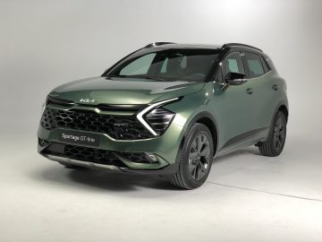 Een slanke groene Kia Sportage GT-line SUV staat geparkeerd in een studio met een smetteloos witte achtergrond.