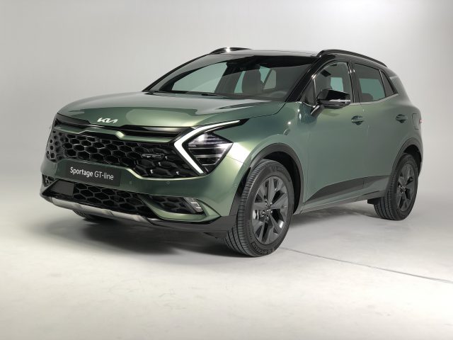 Een groene Kia Sportage GT-line SUV wordt getoond in een studiosetting met een neutrale achtergrond. Het voertuig is schuin geplaatst, waardoor zowel het voor- als het zijprofiel zichtbaar zijn.