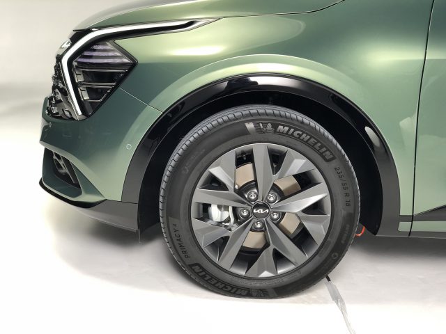 Close-up van het linkervoorwiel en de band van een groene Kia Sportage, met het wielontwerp en het merk Michelin-banden.