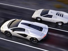 Twee witte sportwagens, waaronder een prachtige Lamborghini Countach, rijden zij aan zij op een weg, waarbij de ene auto iets voor de andere staat, met verschillende ontwerpen uit verschillende tijdperken.