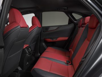 Het interieur van een Lexus NX, met rood en zwart lederen stoelen en een strak, modern design. De afbeelding toont zowel de voorstoelen als de achterstoelen, met zicht op de middenconsole en de ventilatieopeningen achterin.