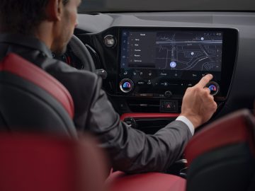 Een persoon in een Lexus NX communiceert met een GPS-navigatiesysteem met aanraakscherm, dat een stadsplattegrond en verschillende menu-opties weergeeft.