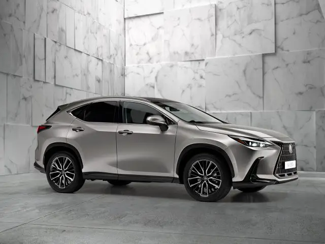 Een Lexus NX staat geparkeerd in een moderne, lichtgrijze ruimte met een gestructureerde, hoekige muur op de achtergrond.