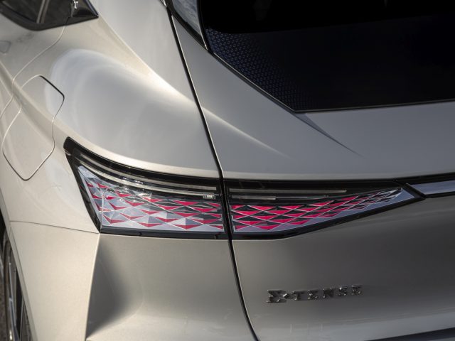 Close-up van het achterlicht en het bovenste gedeelte van een zilveren DS 4-auto, met een geometrisch patroon in het lichtontwerp en het woord "EX-TENSE" op de kofferbak.
