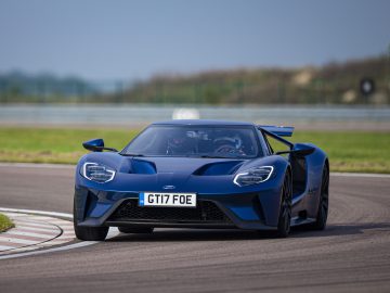 Een strakke blauwe Ford GT neemt moeiteloos een bocht op een racecircuit.