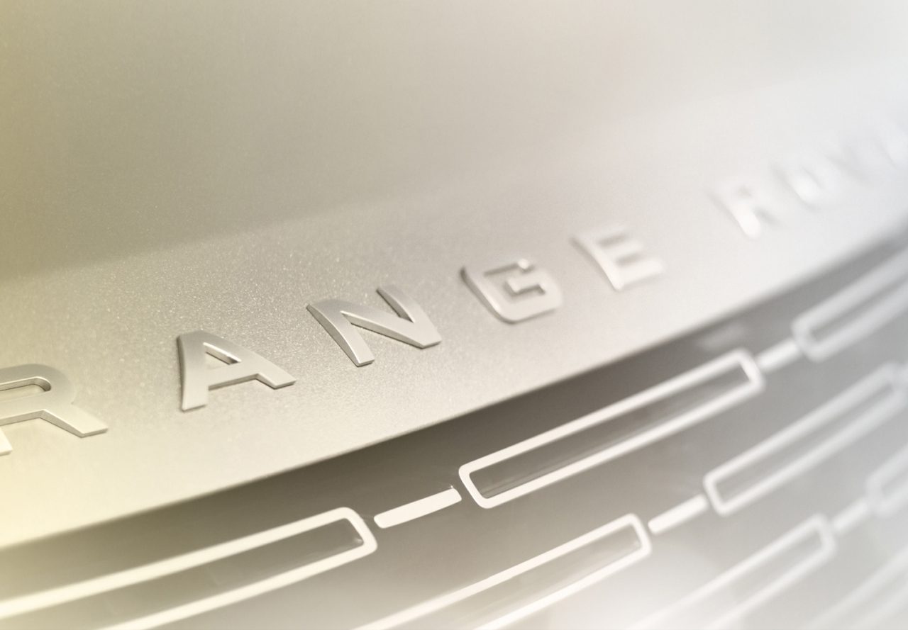 Close-up van de tekst "Range Rover" in reliëf op de grille van een Land Rover-auto.