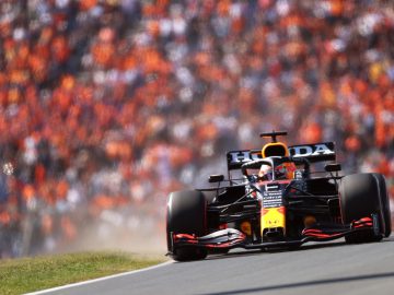 Een raceauto met Honda-logo concurreert op een Formule 1-circuit, met een volle menigte toeschouwers op de achtergrond.