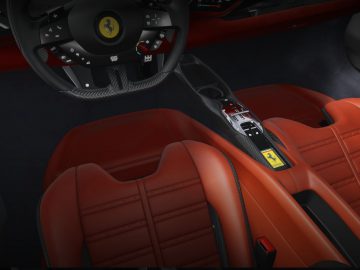 Het interieur van de Ferrari 296 GTB beschikt over roodleren stoelen, een stuur met het iconische Ferrari-logo en een middenconsole uitgerust met een versnellingspook en extra bedieningselementen.