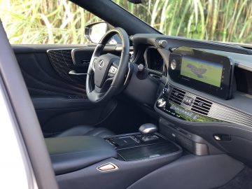 Interieur van een moderne Lexus LS met een zwart lederen dashboard, stuurwiel, versnellingspook en een multimediadisplay.