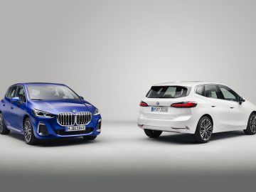 Twee BMW-auto's worden in een studio tentoongesteld tegen een effen achtergrond. De blauwe auto, een BMW 2 Serie Active Tourer, wordt vanaf de linkervoorzijde bekeken, terwijl de witte auto vanaf de rechterachterzijde wordt bekeken.