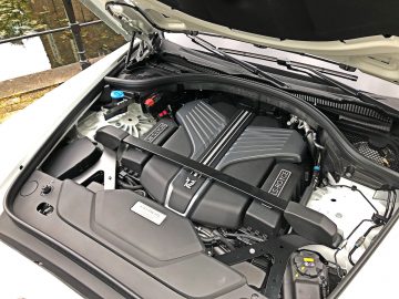 Close-up van de motor van een auto met de motorkap open, met de componenten en details van de motorruimte in een Rolls-Royce Cullinan Black Badge.