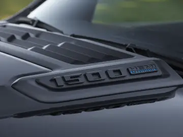 Close-up van een RAM 1500 HEMI eTorque-badge op de motorkap van de truck met een strakke, matte afwerking, met gedetailleerde ventilatieopeningen en contouren, die de kracht en precisie van de RAM 1500 belichamen.