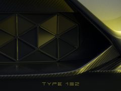 Close-up van de grille met een geometrisch patroon en een metallic afwerking, met onderaan de tekst 