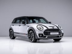 Een zilveren Mini Clubman met zwarte racestrepen en het label 