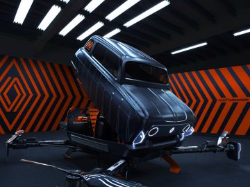 Een futuristisch Renault 4-voertuig met drone-achtige rotors wordt tentoongesteld in een slecht verlichte ruimte met zwarte en oranje geometrische patronen op de muren en het plafond.