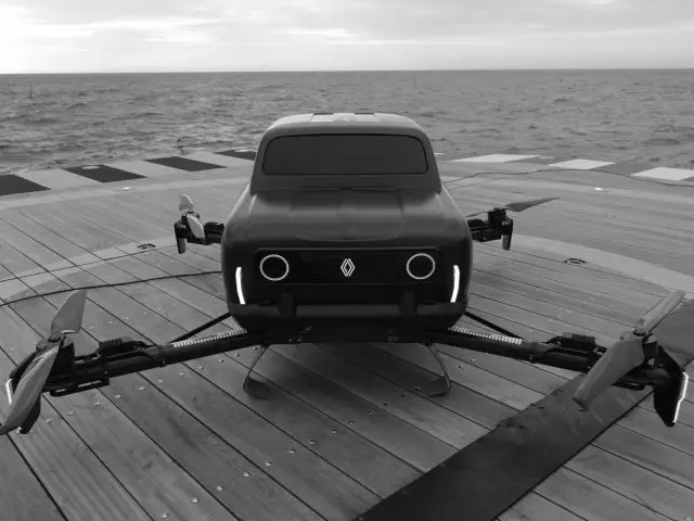 Een zwart-wit beeld van een futuristisch drone-achtig voertuig met vier rotors, dat doet denken aan een moderne Renault 4, geparkeerd op een houten platform aan zee.