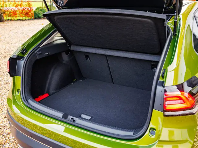 Een groene Volkswagen Taigo SUV met open achterklep, met daarin een lege en ruime bagageruimte met een neergeklapte achterbank en een schoon compartiment.