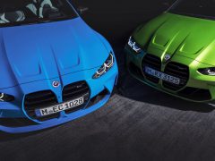 Close-up van de voorkant van twee BMW-auto's, de ene in blauw en de andere in groen, met hun opvallende grille-ontwerpen en koplampen met zichtbare kentekenplaten. Deze nieuwe BMW's zijn te bestellen met historisch logo voor een klassiek tintje.