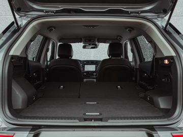 De open kofferbak van de SsangYong Korando e-Motion, met neergeklapte achterbank, creëert een grote vlakke laadruimte. Het interieur is zichtbaar, inclusief de voorstoelen en het dashboard.