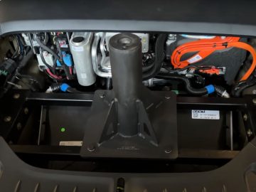 Een open autokap van een Tesla Model S Plaid onthult de interne componenten van de batterij en motoropstelling van het elektrische voertuig, inclusief kabels, bedrading en mechanische onderdelen.