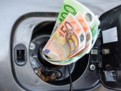 Eurobankbiljetten die in een open brandstoftank van een voertuig worden gestoken, symboliseren de kosten van benzine.