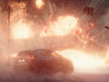 Er vindt een dramatische explosie plaats in een stedelijk gebied, waarbij puin door de lucht vliegt. Een Lexus op de voorgrond rijdt weg van de explosie terwijl andere voertuigen en constructies worden getroffen.