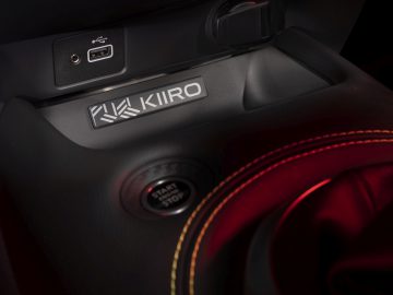 Close-up van het interieur van een Nissan Juke met een USB-poort, stopcontact, start/stop-knop en een Kiiro-logo eronder.