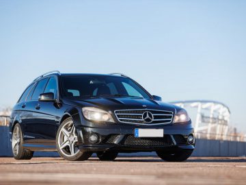 Zwarte Mercedes-Benz stationwagen geparkeerd op een verhard oppervlak en straalt een sfeer van verfijning uit die doet denken aan de legendarische aanwezigheid van Michael Schumacher, met een subtiel onscherpe achtergrond.