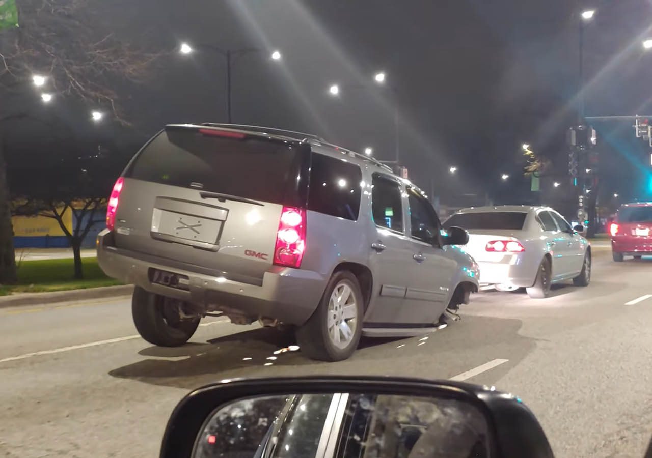 Een zilveren SUV met de achterwielen van de grond wordt midden op de weg naar voren gekanteld, waardoor er verkeershinder ontstaat.