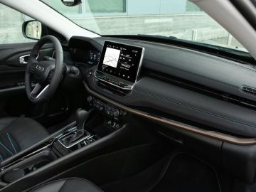 Het interieur van een moderne Jeep toont het dashboard, het stuur, het infotainmentsysteem en de versnellingspook.