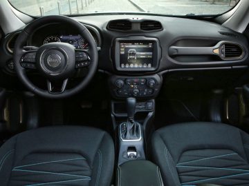 Interieur van een Jeep met het dashboard, het stuur, de middenconsole met touchscreen, de versnellingspook en twee voorstoelen. De nadruk ligt op het dashboard en het zitgedeelte voorin.