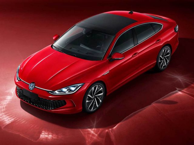 Een rode Volkswagen sedan staat geparkeerd op een levendig rood oppervlak, waardoor de strakke lijnen en zwartgetinte ramen goed tot hun recht komen.