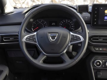 Stuur en dashboard van de Dacia Jogger, met een centraal display met pictogrammen, snelheids- en toerentellermeters en verschillende bedieningsknoppen.