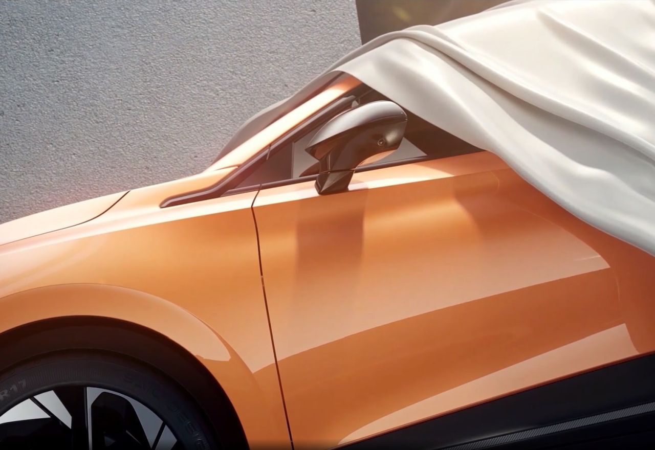 Een gedeeltelijk overdekte oranje elektrische auto met een wit laken over het dak en de zijspiegel gedrapeerd.
