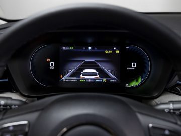 Close-up van het digitale dashboard van een MG5 Electric met een rijhulpfunctie met een centraal scherm met een voertuig, rijstroken en verschillende indicatoren voor snelheid, afstand, batterij en rijmodus.