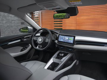 Modern auto-interieur met een zwart en grijs kleurenschema, een touchscreen-infotainmentsysteem, een multifunctioneel stuur en een strak dashboardontwerp. De MG5 Electric verbetert dit met zijn milieuvriendelijke prestaties en geavanceerde technische kenmerken.