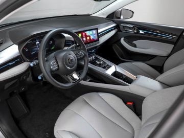 Het interieur van de MG5 Electric is voorzien van een strak stuur, geavanceerde touchscreen-displays voor het infotainment en het instrumentenpaneel, en lichtgrijze lederen stoelen, die modern design combineren met geavanceerde technologie.