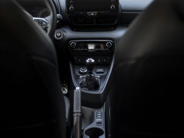 Binnenaanzicht van een Toyota GR Yaris met het dashboard, het stuur en de middenconsole met versnellingspook en bekerhouders.